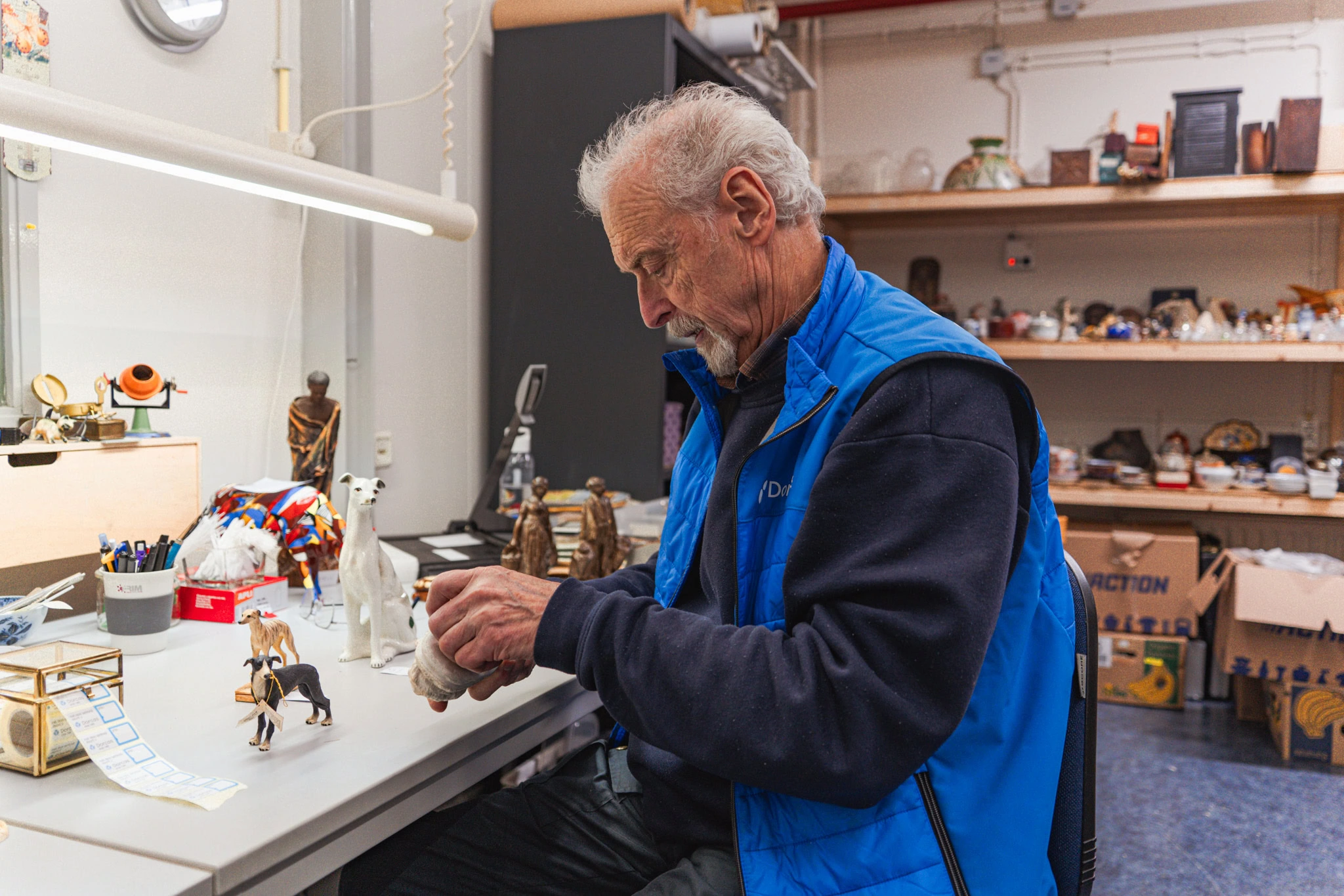 Kunstambachtspecialist werkt aan handgemaakte sculpturen en keramiek in werkplaats van Dorcas, gericht op sociale en ambachtelijke projecten in Nederland.