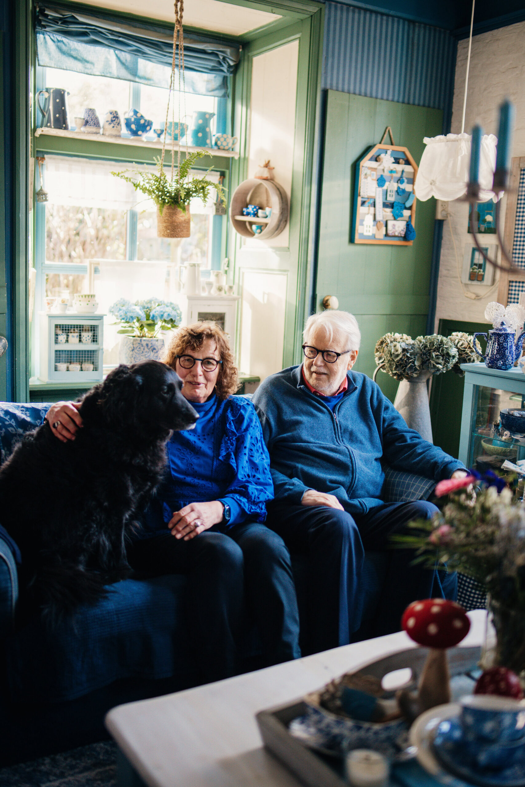 Janneke en Dirk Jan Groot zitten met de hond op de bank in hun woonkamer.
