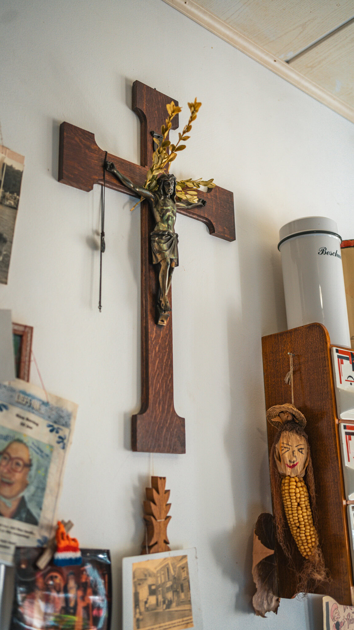Houten kruis met Jezusfiguur en bloemen, religieus wanddecoratie in interieur.