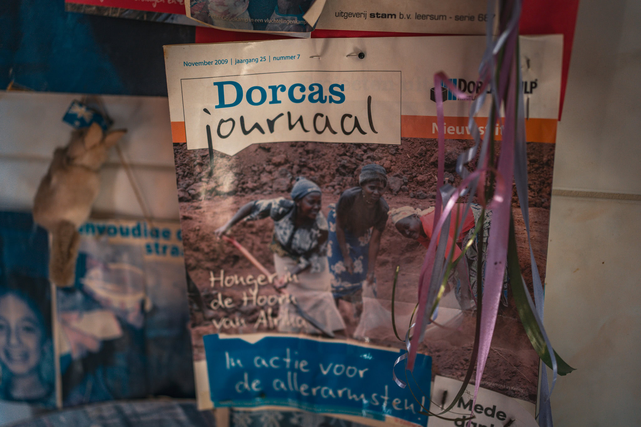 Persfoto van het Dorcas Journaal met vrouwen die in Kenia werken aan landbouwprojecten voor hulp en armoedebestrijding, versierd met linten.