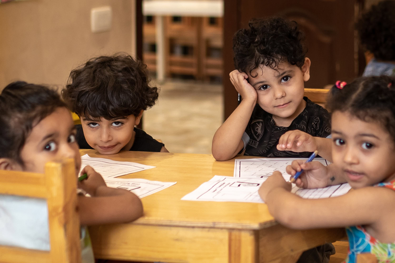 Kinderen zitten aan een tafel en maken knutselwerkjes in een klaslokaal.