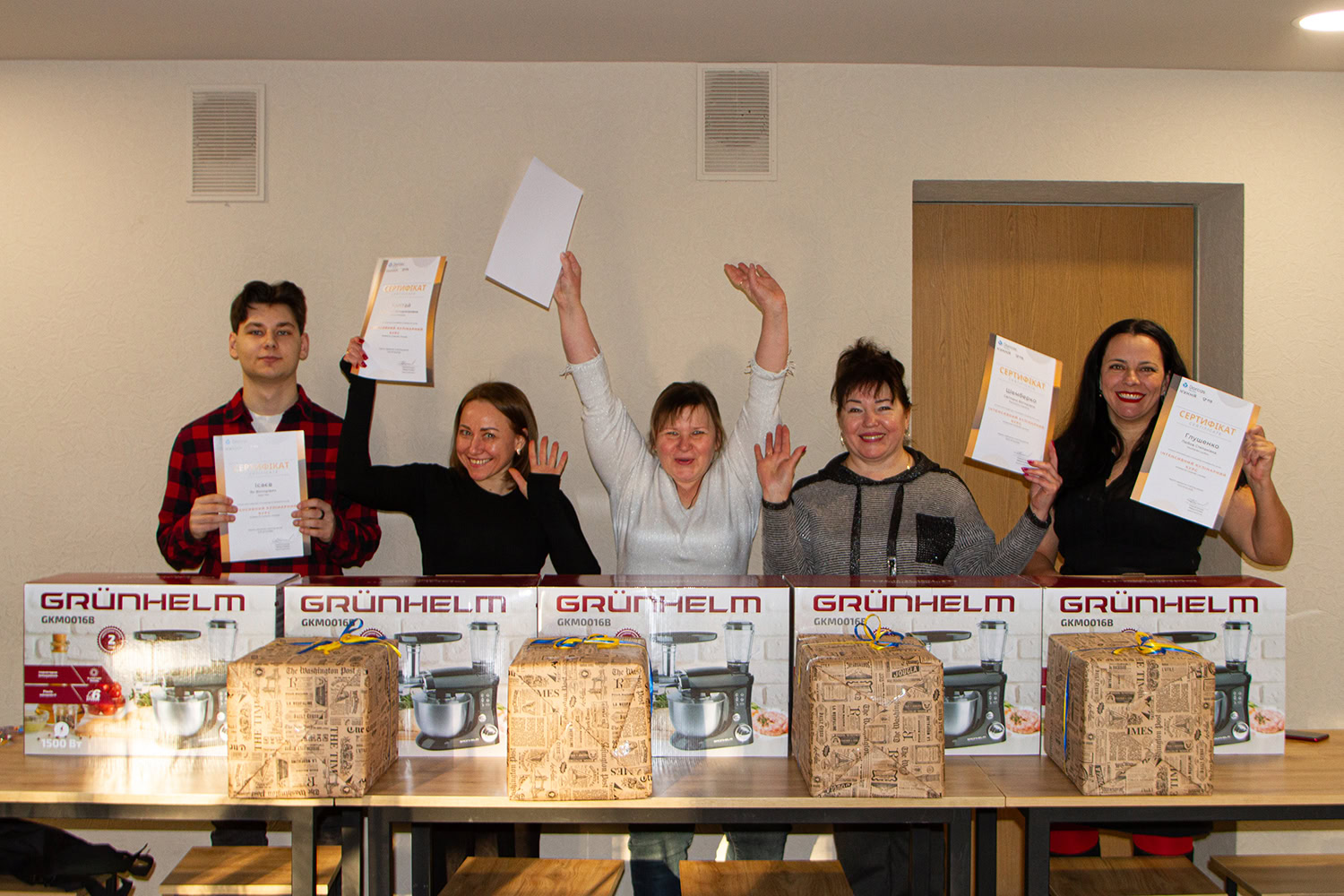 Gelukkige groep mensen die certificaten vasthouden en feest vieren met nieuwe huishoudelijke apparaten.